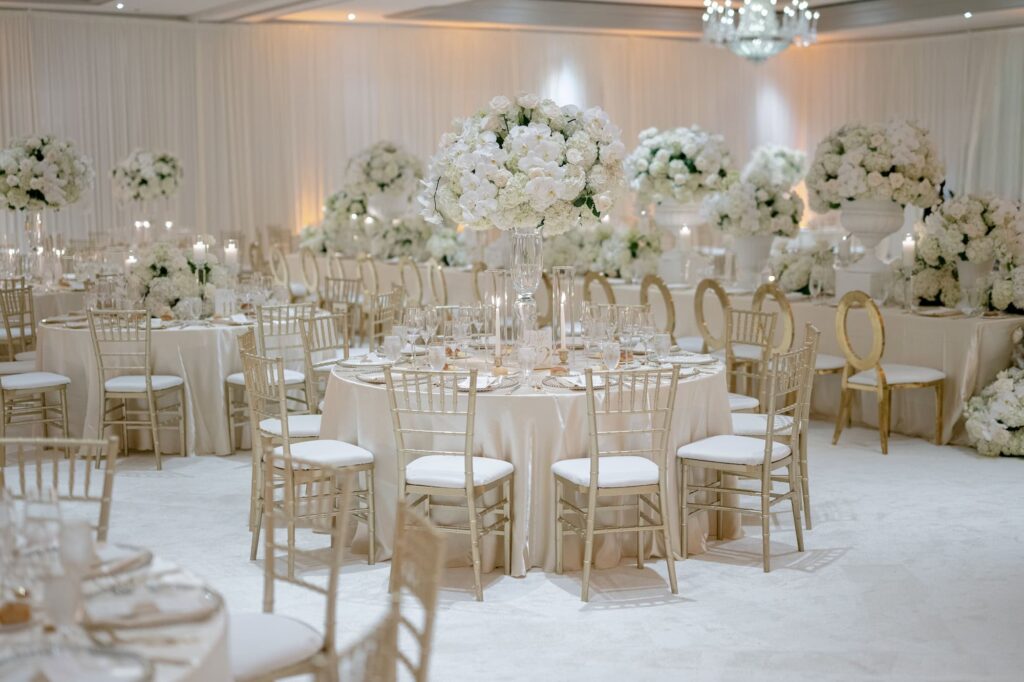 Garnier trumpet vase containing white florals on reception table with taper candles