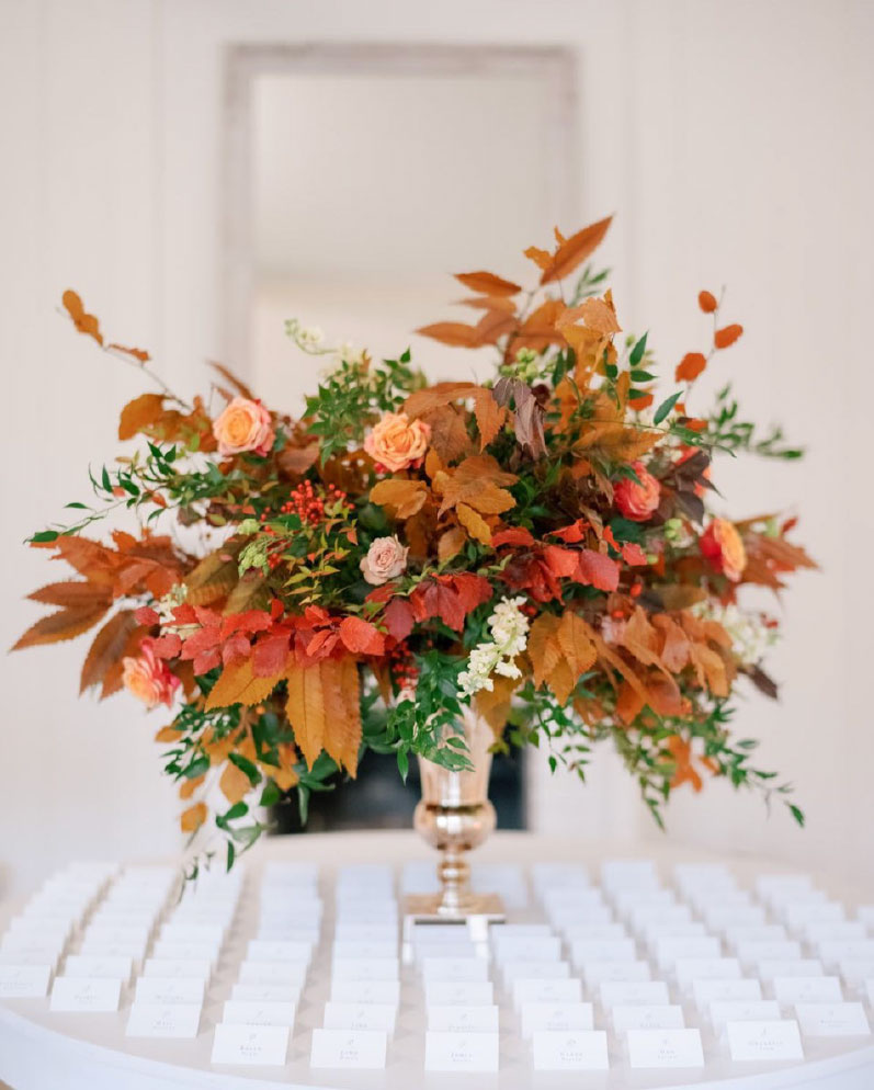 Fall floral color palette in gold trumpet vase on reception place card table