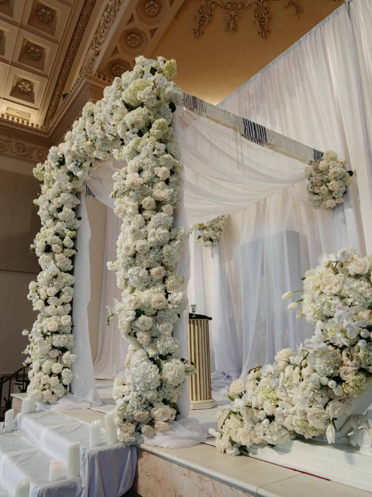 Chuppah wedding canopy drapery surrounded by white florals and candles